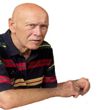 &Auml;lterer Mann mit Glatze und einem Kurzhaarschnitt, tr&auml;gt ein gestreiftes Poloshirt und schaut nachdenklich zur Seite.