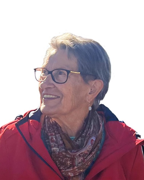 L&auml;chelnde &auml;ltere Frau mit Brille, roter Jacke und Halstuch, blickt nach oben vor hellem Hintergrund.