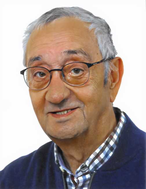 Portr&auml;t eines &auml;lteren Mannes mit Brille, l&auml;chelnd, in einem karierten Hemd und einer blauen Jacke vor wei&szlig;em Hintergrund.