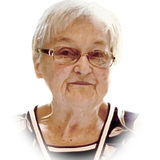 Porträt einer älteren Frau mit Brille und kurzem, grauem Haar, vor einem weißen Hintergrund.