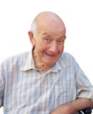 Lächelnder älterer Mann mit Glatze, trägt ein kariertes Hemd, sitzt auf einem Rollstuhl vor weißem Hintergrund.