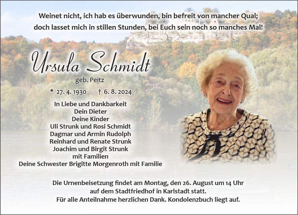 Frau mit hellem Haar und Schmuck l&auml;chelt auf einer Traueranzeige, umgeben von einem sanften Landschaftshintergrund.