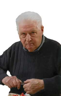 &Auml;lterer Mann mit wei&szlig;em Haar, der konzentriert mit einer Klinge an einem Objekt arbeitet, tr&auml;gt einen dunklen Pullover.