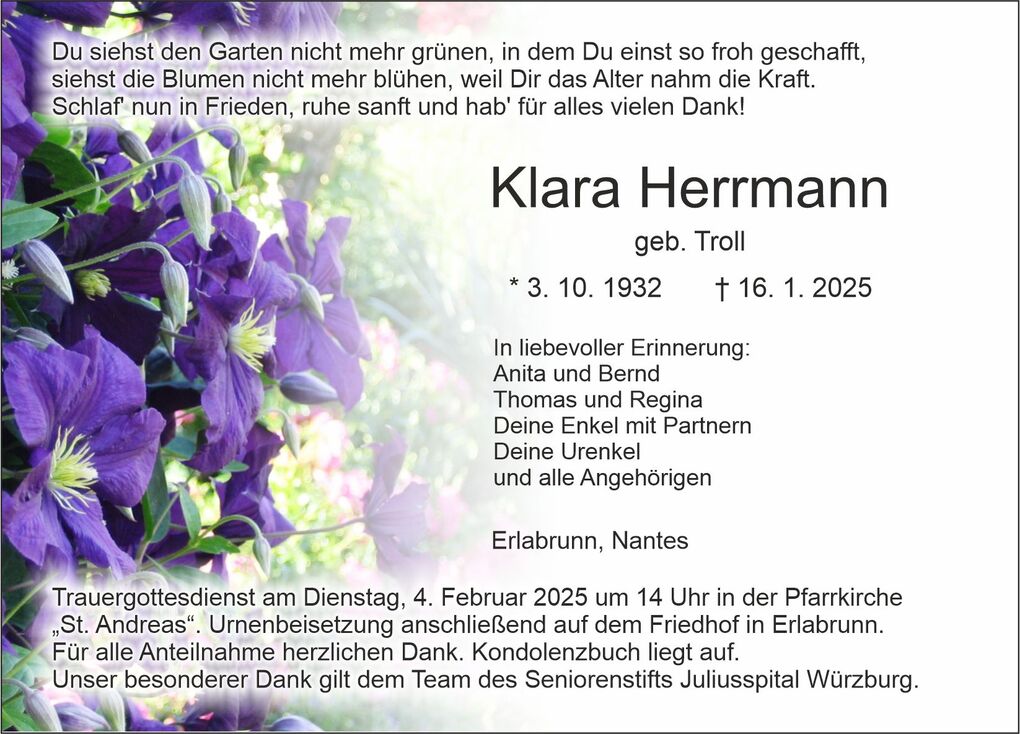 Bl&uuml;hende lila Clematis umrahmt eine Trauerkarte mit Inschrift &uuml;ber Klara Herrmanns Lebensdaten und Ehrung.