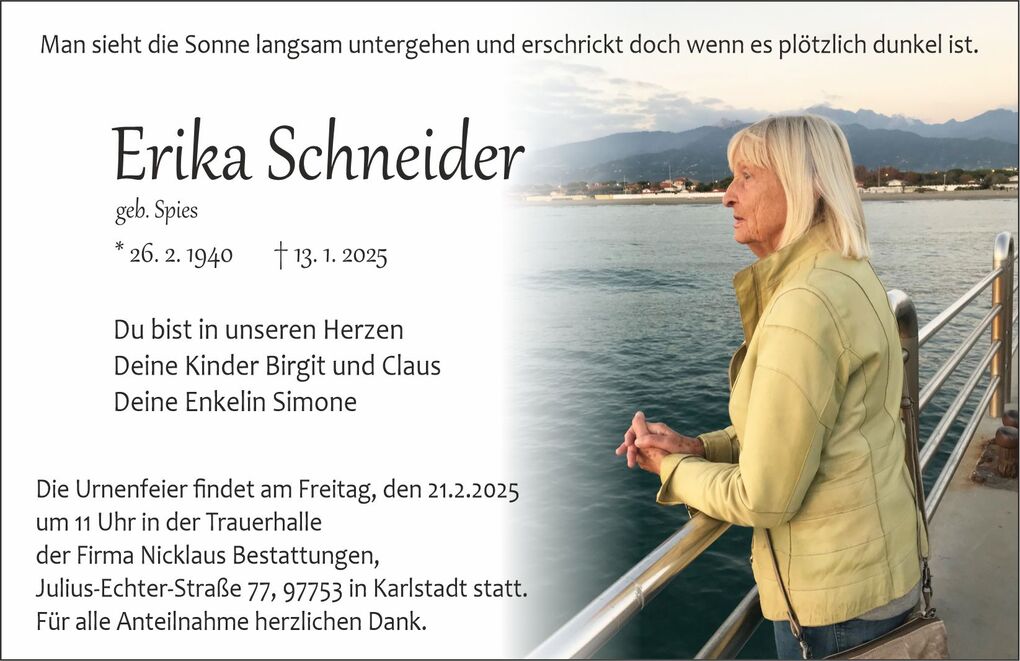 Frau mit blonden Haaren in gelber Jacke, die am Wasser steht und den Sonnenuntergang betrachtet.
