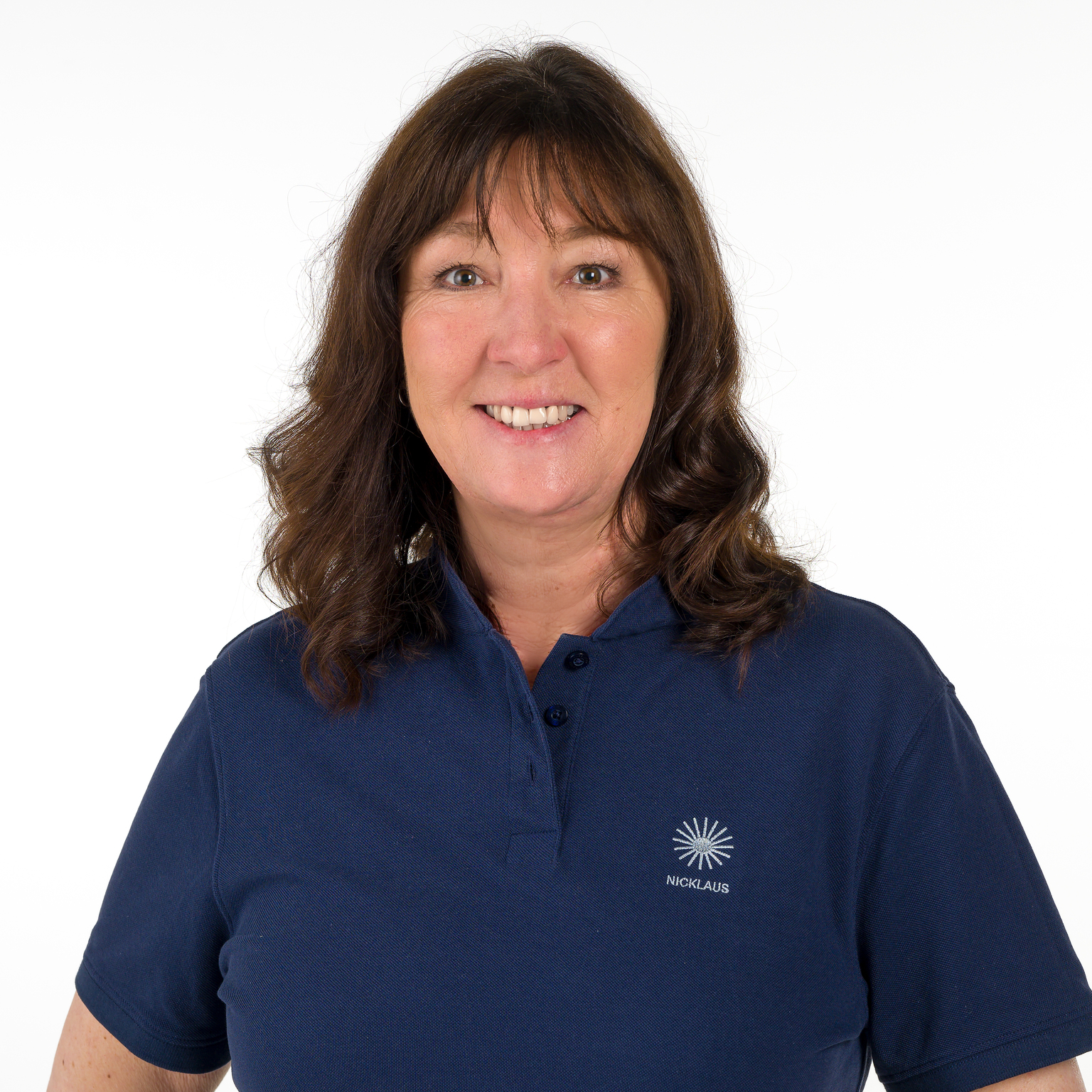 Portr&auml;t einer l&auml;chelnden Frau mit lockigem, braunem Haar, die ein dunkelblaues Poloshirt tr&auml;gt. Hintergrund ist einheitlich wei&szlig;.